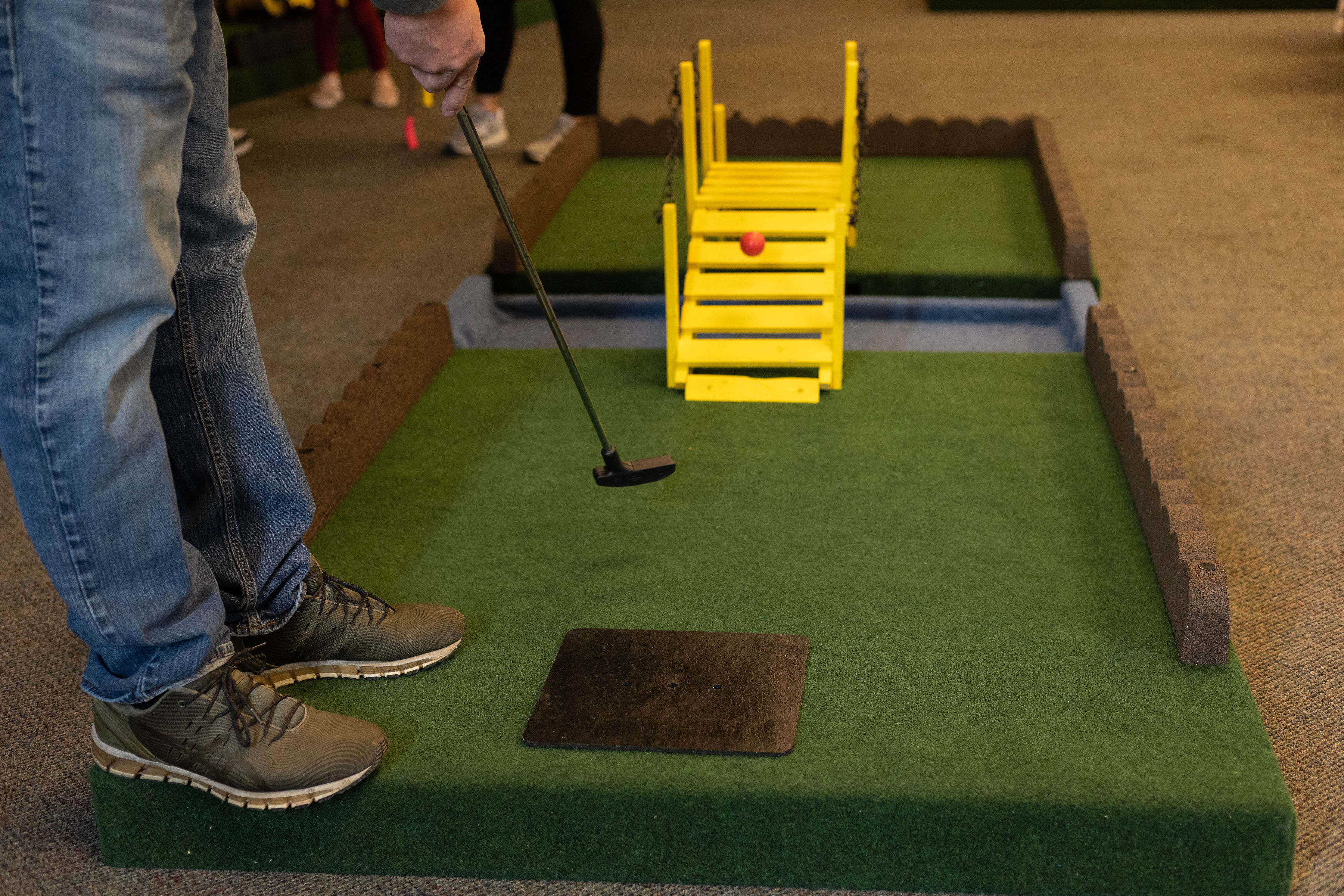 A player putting on the Steel City mobile mini golf course
